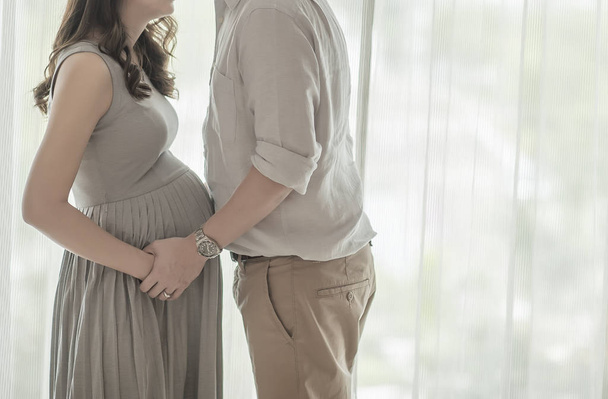 Pregnant woman with husband in front of the window - Foto, Imagem