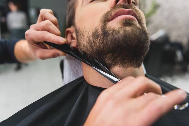 Skillful hairdresser cutting stubble of client - Foto, imagen