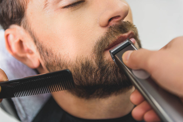 Professional barber using electric machine for haircut - Foto, Bild
