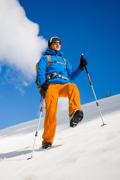 Hombre con bastones de trekking pasa por la nieve en las montañas
. - Foto, imagen