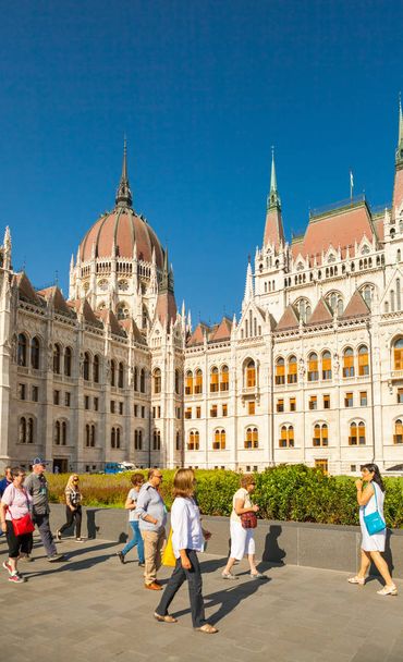 Budapest, Hungría - 16 de junio de 2016: Grupo de turistas pasando por el edificio de Parlamento húngaro en Budapest, Hungría - 16 de junio de 2016 - Foto, Imagen