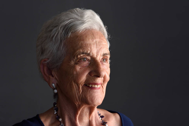 Portréja egy idősebb nő, a szürke háttér - Fotó, kép