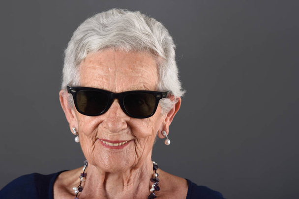 Portréja egy idősebb nő, a szürke háttér - Fotó, kép