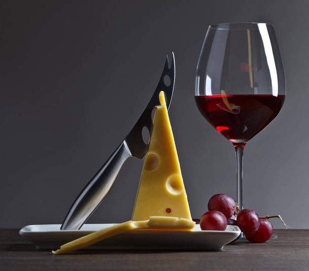 Cheese and red wine on a old wooden table - Photo, Image