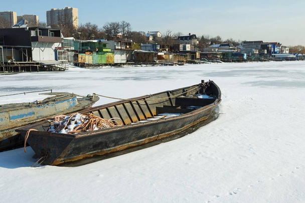 Old fishing boat frozen in the ice in river. - Foto, afbeelding