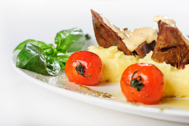 М'ясо баранини запечене з вершковим соусом, картопляним пюре та вишневими помідорами
 - Фото, зображення