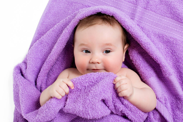 Newborn baby lying down and smiling in a purple towel - Photo, image