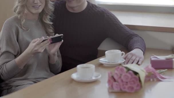 Gelukkige paar kijken op mobiel en lachen in de caf . - Video