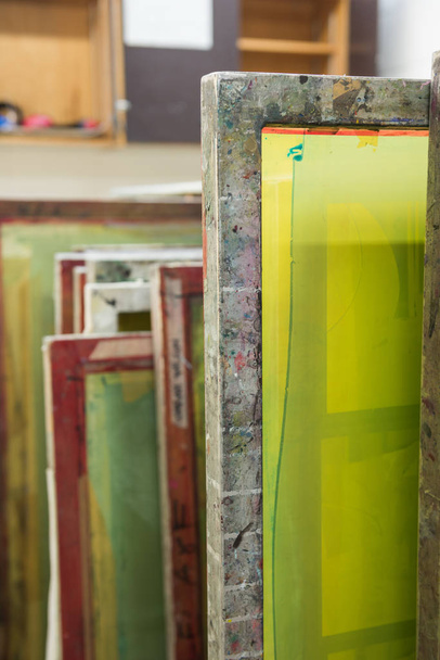 Silk screen printing screens stored in a wooden rack ready for printing. - Fotó, kép