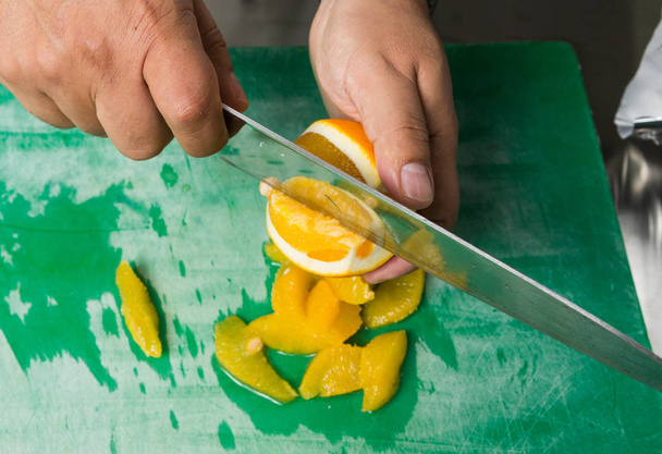 A juicy orange being sliced into segments. - Zdjęcie, obraz