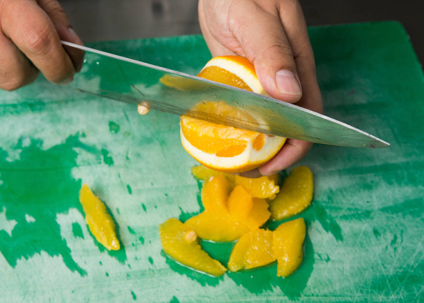 A juicy orange being sliced into segments. - Foto, afbeelding