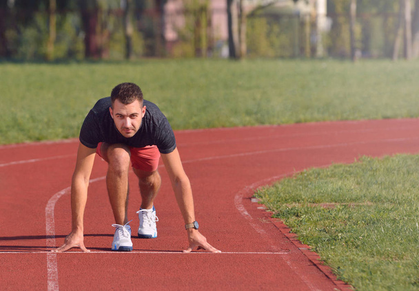 Homme athlétique sur la piste commence à courir. Concept de fitness sain avec mode de vie actif
. - Photo, image