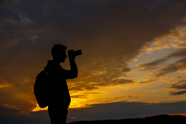 silueta fotografa fotografujícího krajinu při západu slunce - Fotografie, Obrázek