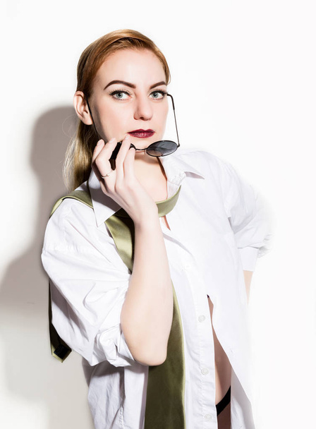 naked young woman in a mans white shirt with green tie holding glasess - Foto, afbeelding