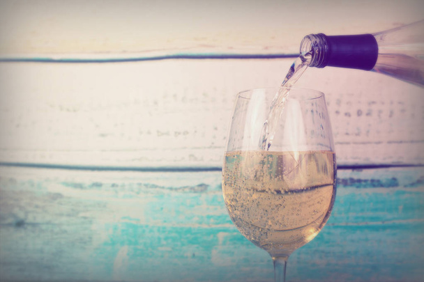 Склянку білого вина наливають з пляшки
 - Фото, зображення