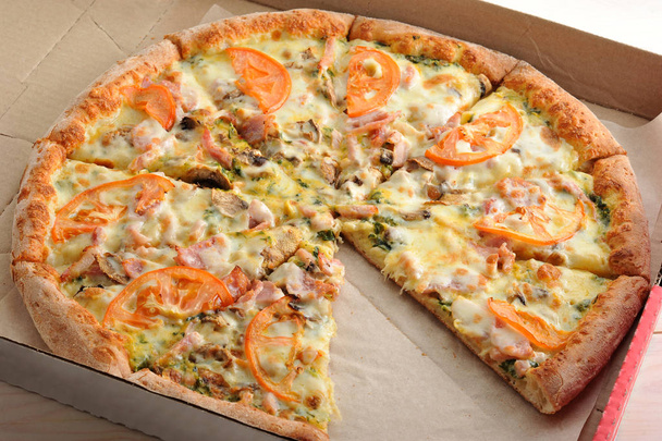 Pizza in Scheiben geschnitten mit Champignons, Tomaten, Käse und Speck - Foto, Bild
