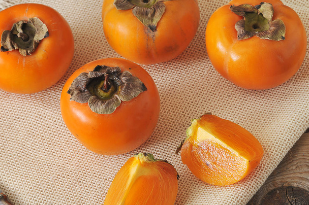persimmon whole and cut into pieces on canvas - Foto, imagen