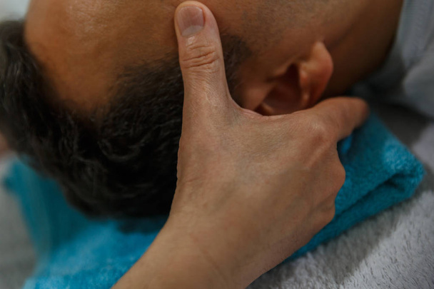 Bir masaj terapisti ellerini bir hastanın kafasına geçerlidir. - Fotoğraf, Görsel