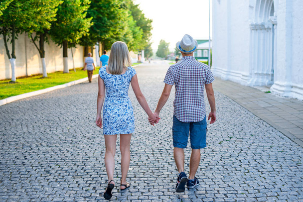 Man and woman are on stone pavement holding hands, summer in city, concept of the event young family, newlyweds complex relationship. Lifestyle in romance. Outdoors. - Photo, image