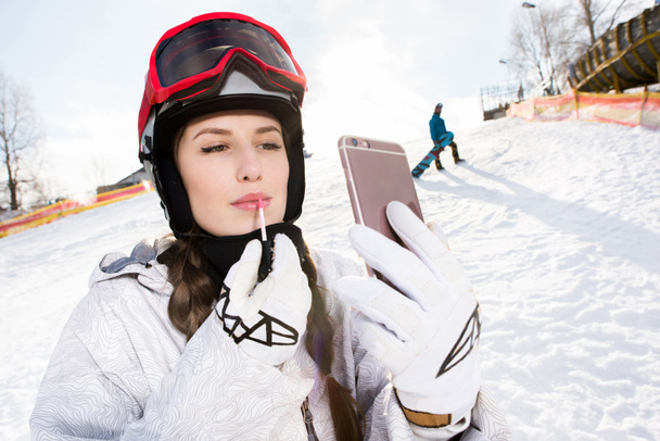 snowboarder femenino aplicando brillo labial
 - Foto, Imagen