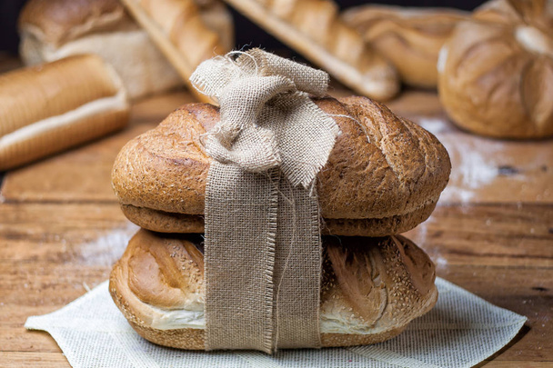 pão diferente na mesa de madeira, farinha, pano de saco
 - Foto, Imagem