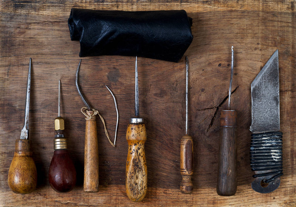 Bőr kézműves eszközök egy fából készült háttér. Craftmans íróasztal. - Fotó, kép