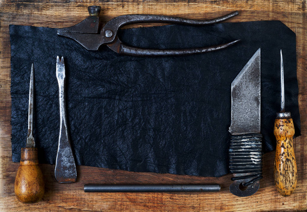 Werkzeuge aus Leder auf einem hölzernen Hintergrund. Schreibtisch für Handwerker. - Foto, Bild