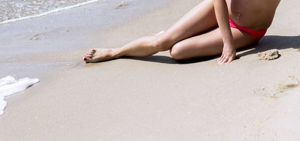 piernas y zona de bikini de la mujer tomando el sol junto al mar
 - Foto, imagen
