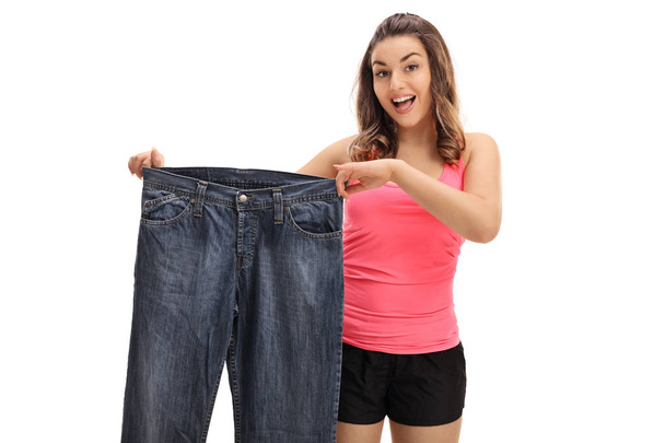Happy woman holding a pair of oversized jeans - Foto, Imagem