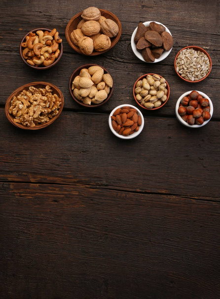 Group of delicious dried fruits over a wooden background. Nuts, almonds, pistachios - Photo, Image