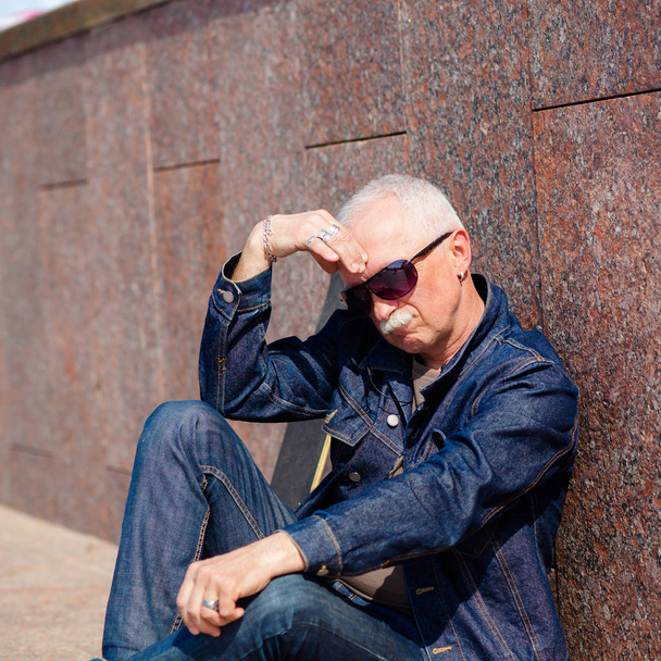 Senior man sitting and dreaming on the pavement near a skateboard - Fotografie, Obrázek