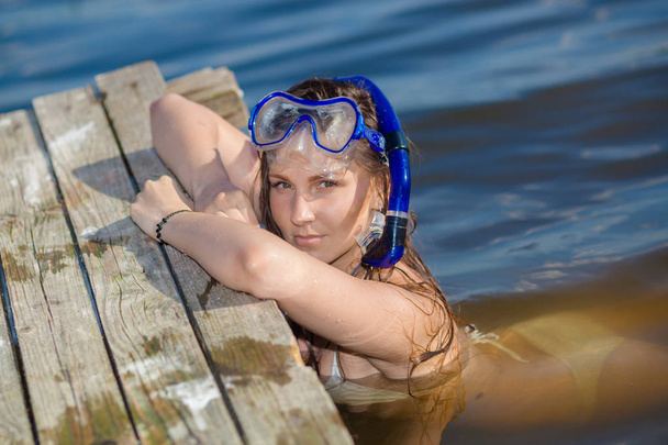 Szczęśliwa dziewczyna nurkowania w pływanie maski i fajki, w pobliżu starego drewnianego molo. - Zdjęcie, obraz