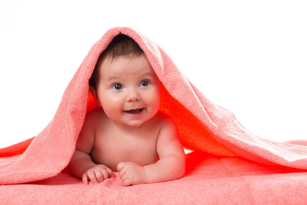 Bebé recién nacido acostado y sonriendo en una toalla de color terracota
 - Foto, imagen