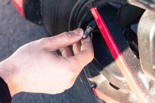 Man opening valve tire cap of car wheel  - Photo, Image