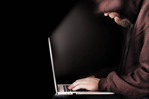 Hooded computer hacker using laptop - Valokuva, kuva