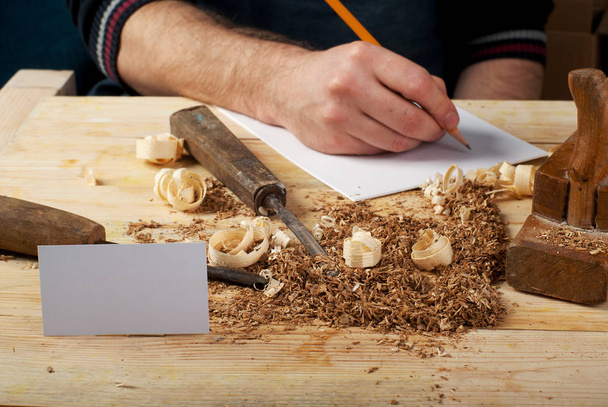 Tarjeta de visita sobre mesa de madera para herramientas de carpintería con serrín
. - Foto, Imagen