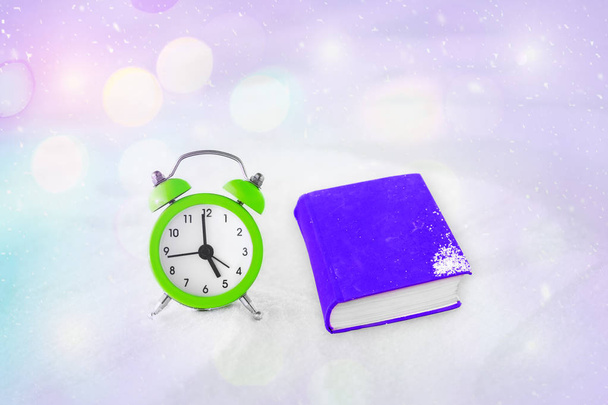 Time to read. Book and vintage alarm clock on the snow. The concept of Christmas and New Year. Magic composition. Switched to winter time. Good morning. Waiting of holiday. In anticipation of the exam - Valokuva, kuva