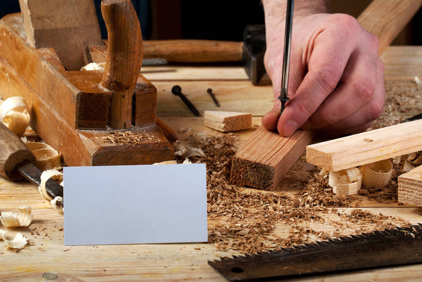 Visitenkarte auf Holztisch für Zimmermannswerkzeuge mit Sägemehl. - Foto, Bild