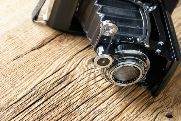 old folding camera on a textured rustic wooden surface. - Photo, Image