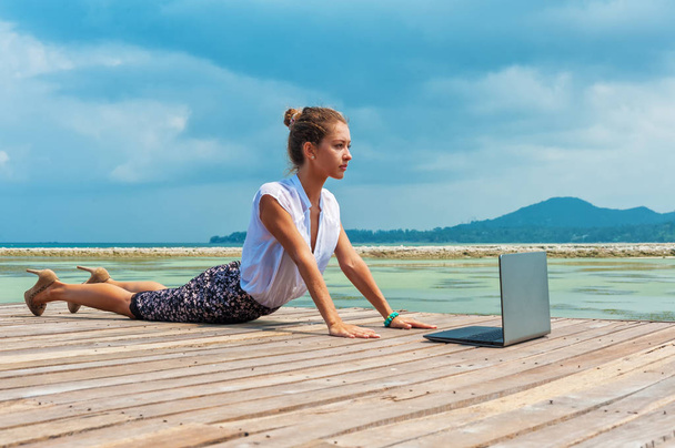 Woman in office suit doing yoga with laptop - Foto, afbeelding
