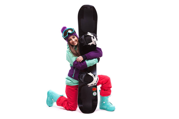 Ski vrouw op één knie hugs snowboard - Foto, afbeelding
