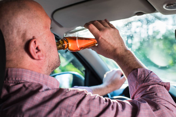 Ο άνθρωπος που πίνει αλκοόλ στο αυτοκίνητο. - Φωτογραφία, εικόνα