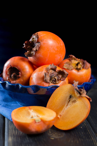 Cachi arancio maturi hachiya in ciotola blu
 - Foto, immagini