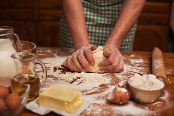 Senior man hands knead dough on table in home kitchen - Foto, imagen