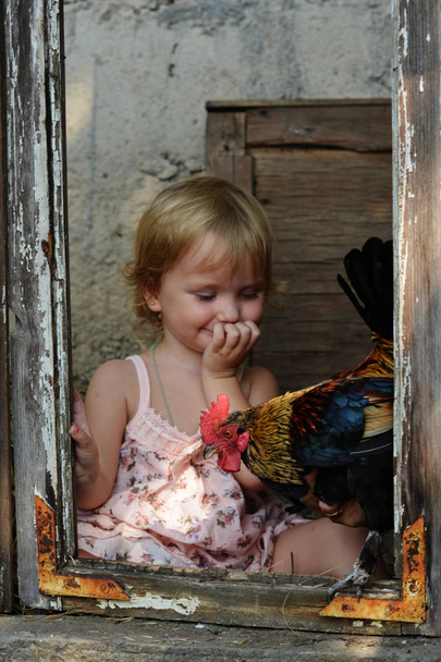 Πορτρέτο του ένα μικρό κορίτσι στο παράθυρο του ένα ερειπωμένο σπίτι.  - Φωτογραφία, εικόνα