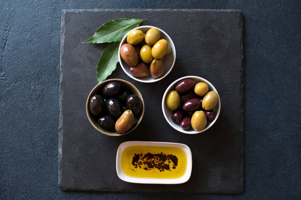 Olives and olive oil on dark stone - Fotó, kép