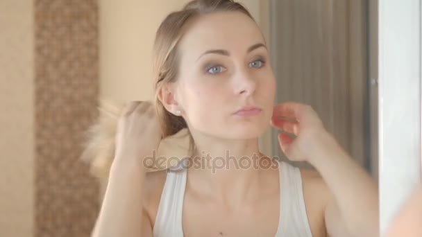 Beautiful young woman checking her face in the mirror - Video