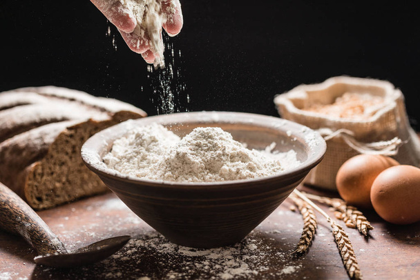 pouring flour in black bowl - Foto, afbeelding