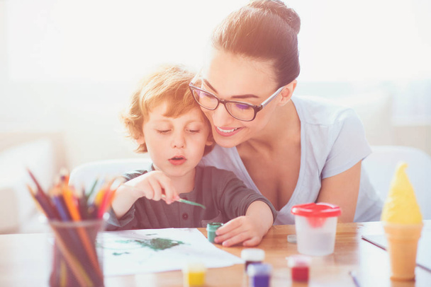 Smiling mother teaching her son to draw - 写真・画像