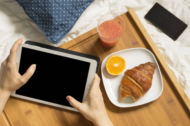 Femme travaillant avec sa tablette et prenant le petit déjeuner
 - Photo, image